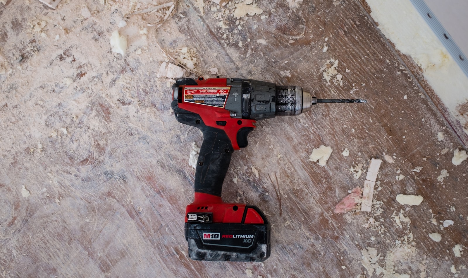 A cordless drill resting on a dusty worksite floor