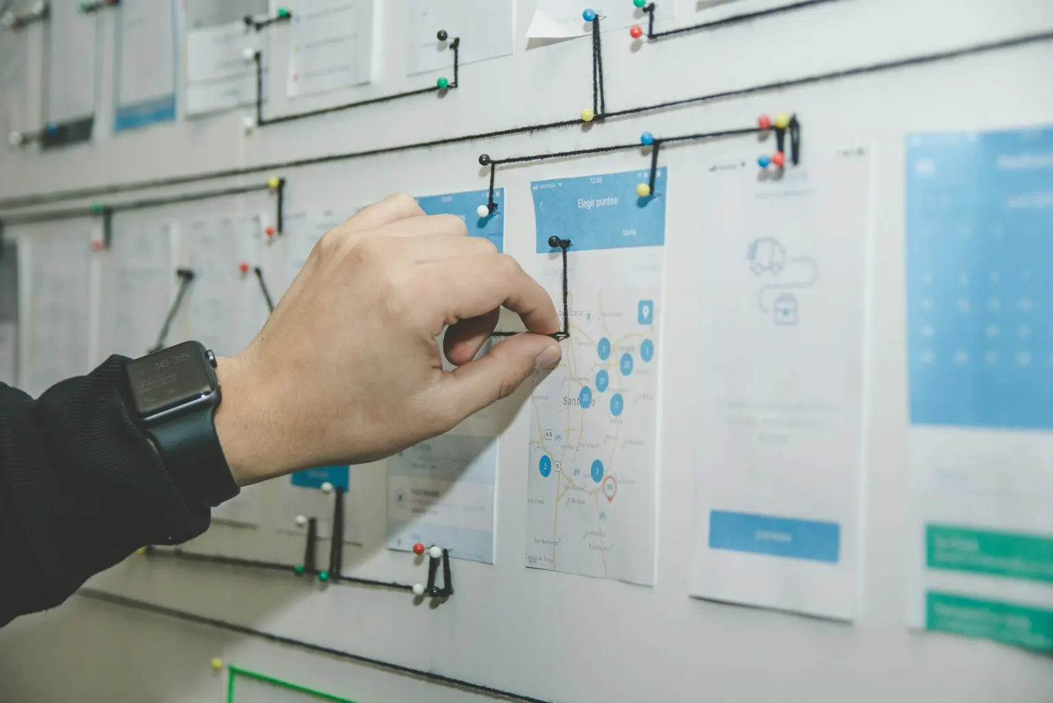 A hand pinning website page layouts to a planning wall