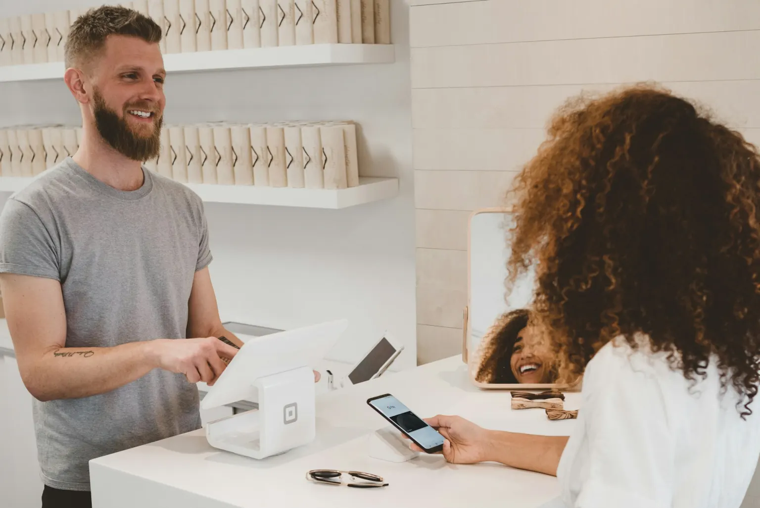 A shop owner serving a customer at a bright modern counter